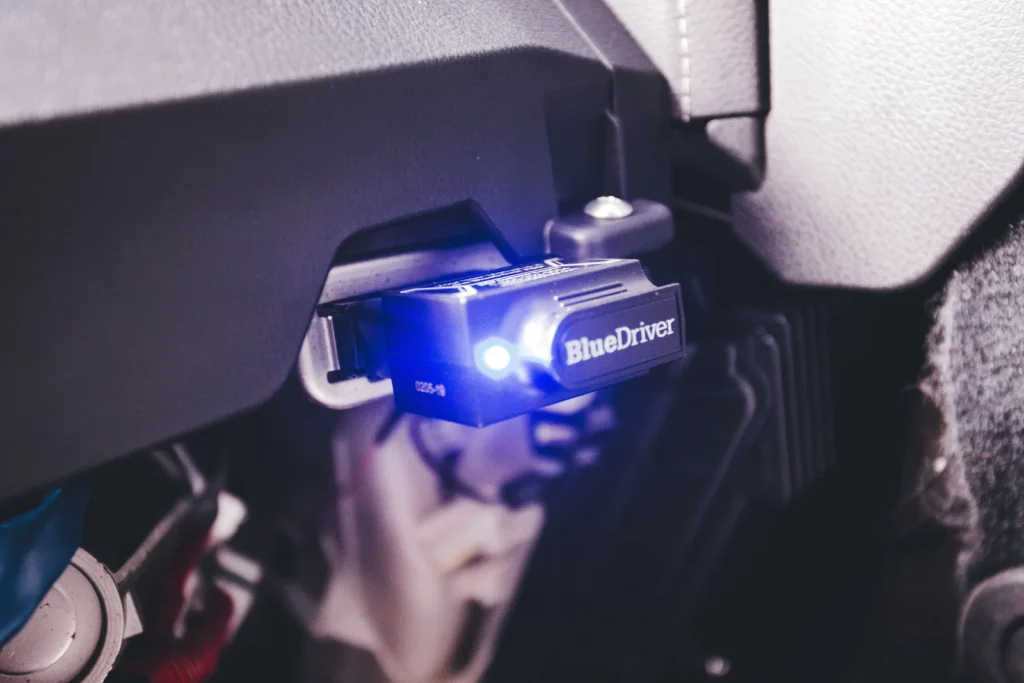 An electronic code reader plugged into a vehicle diagnostic port under the dashboard