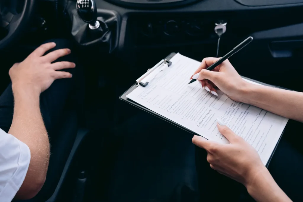 Close-up of hands filling in a service form on a clipboard inside a vehicle