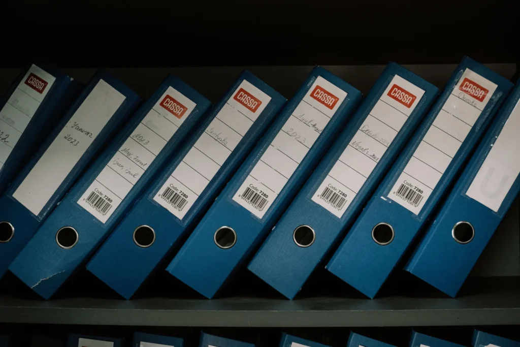 A row of labelled binders holding archived records on a shelf