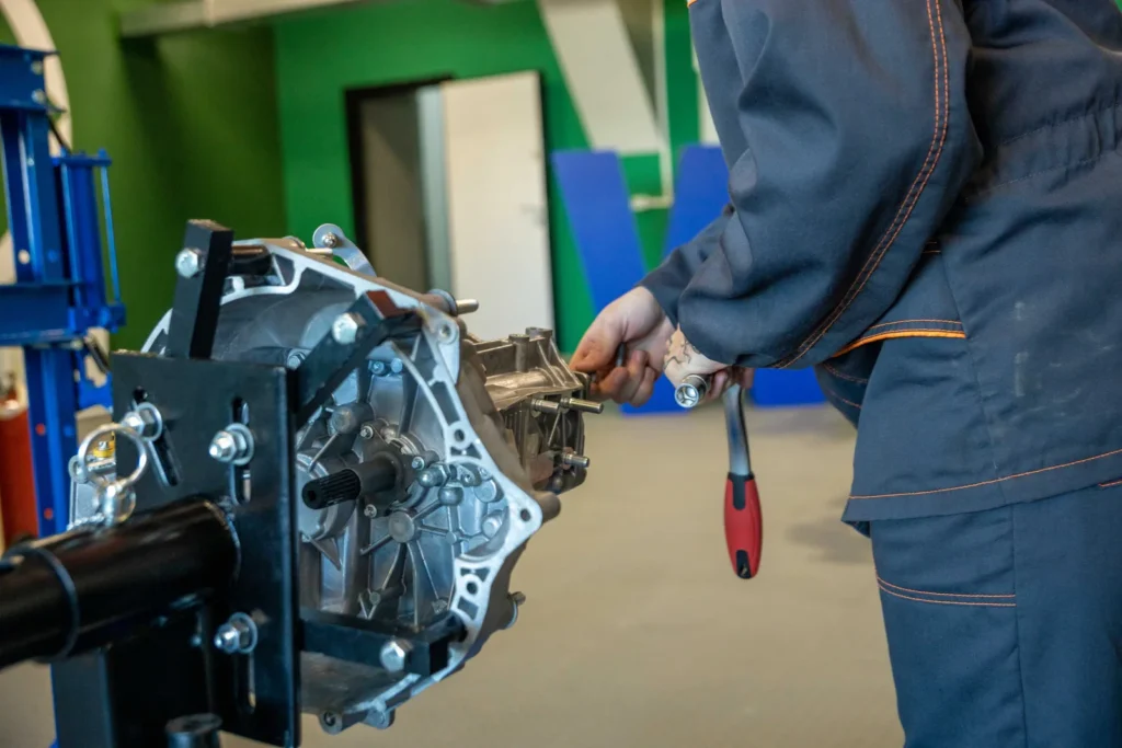 A mechanic using tools to repair a car transmission in a workshop