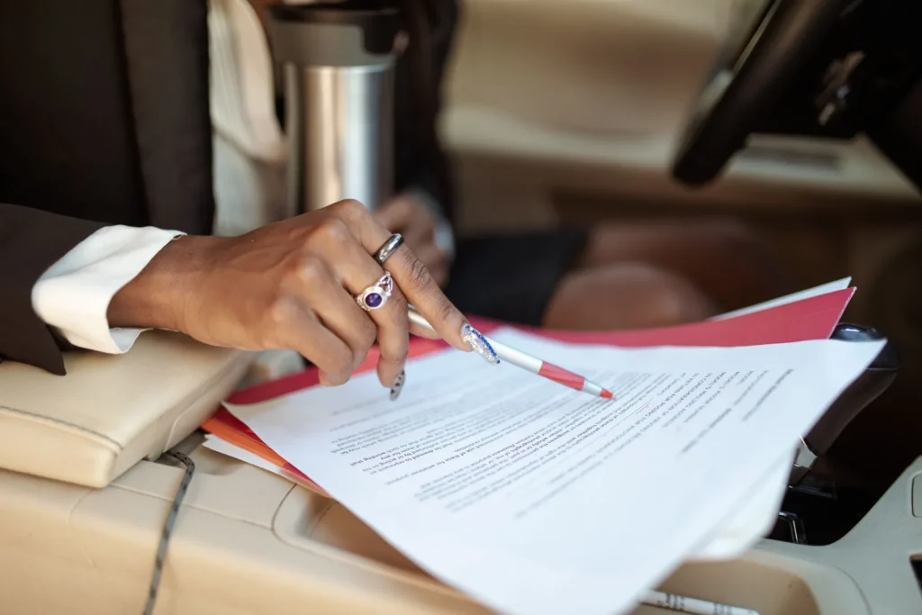 Close-up of a person reviewing warranty and repair paperwork inside a car