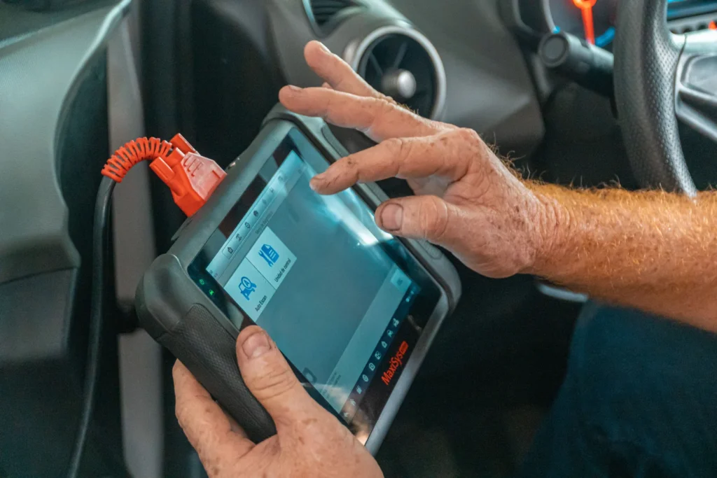Technician holding a diagnostic scan tool inside a vehicle