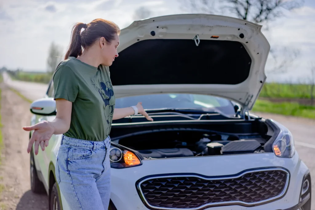 Driver standing beside a car with the hood raised at the roadside