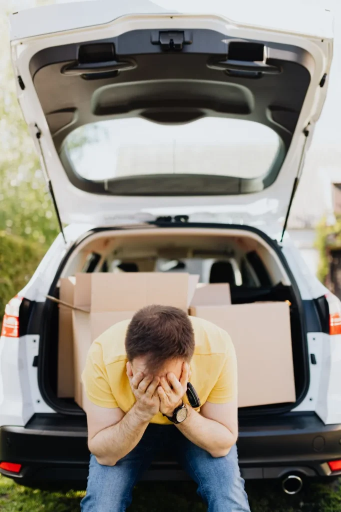 A person sitting in the open trunk of a car with the tailgate raised