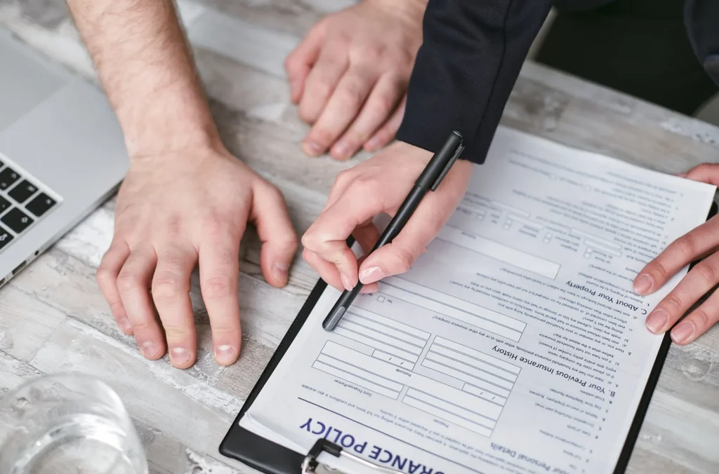 Hands signing warranty claim paperwork on a clipboard