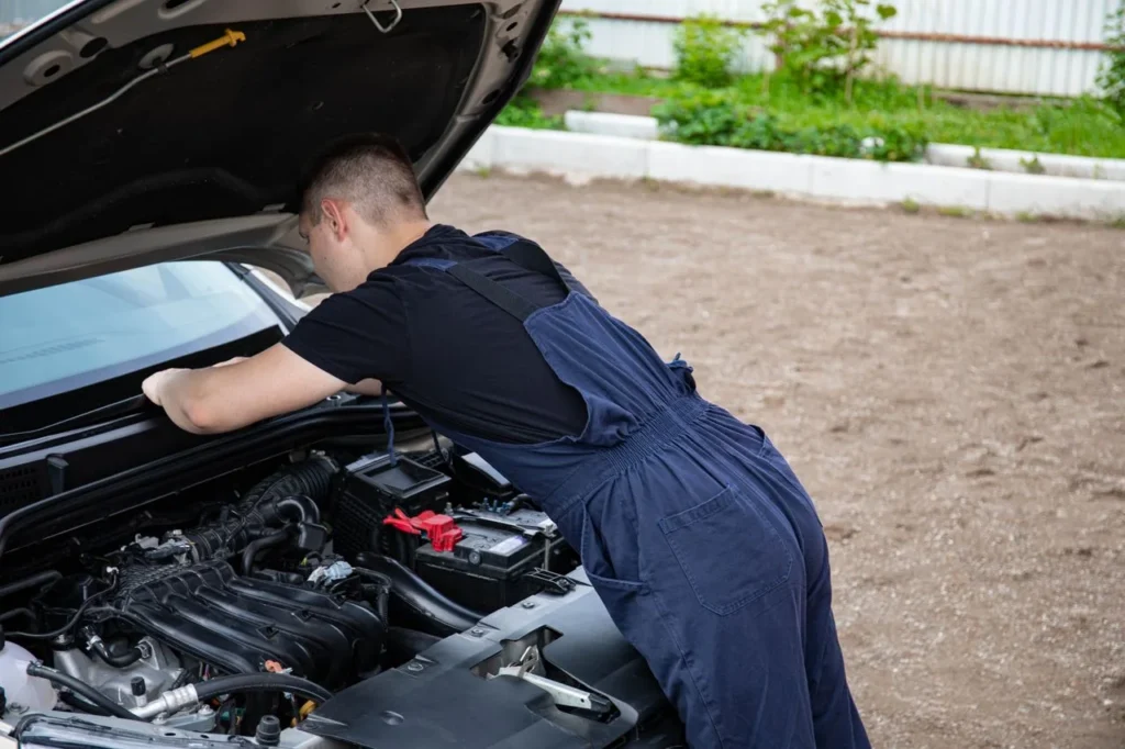 Mechanic leaning into the engine bay of a car with the hood raised