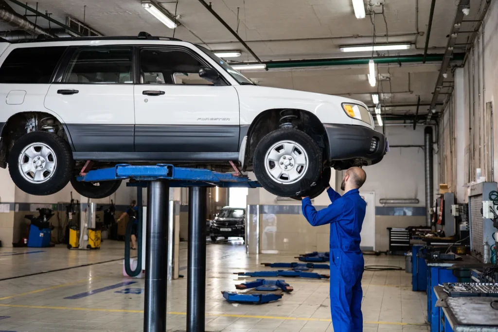 Mechanic inspecting an SUV raised on a shop lift