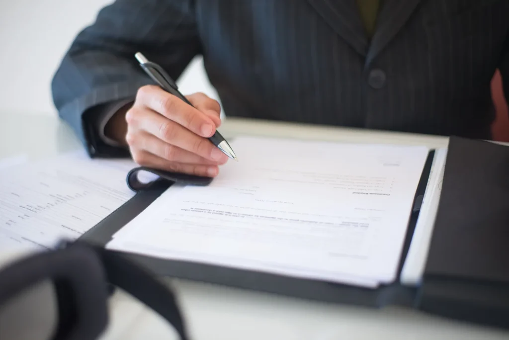 Hand signing a vehicle warranty claim form with a pen